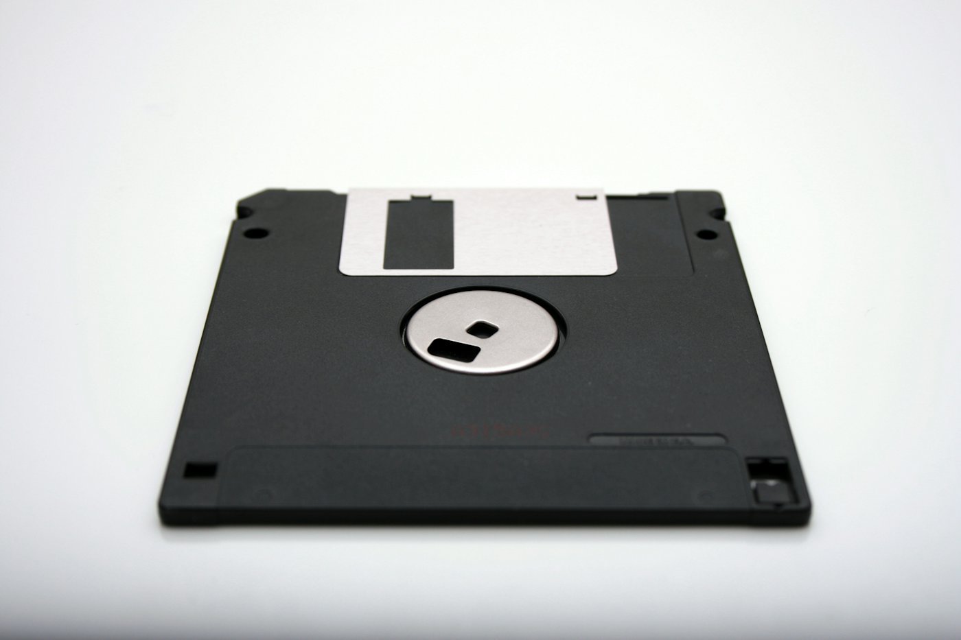 An old black floppy diskette on a plain surface.