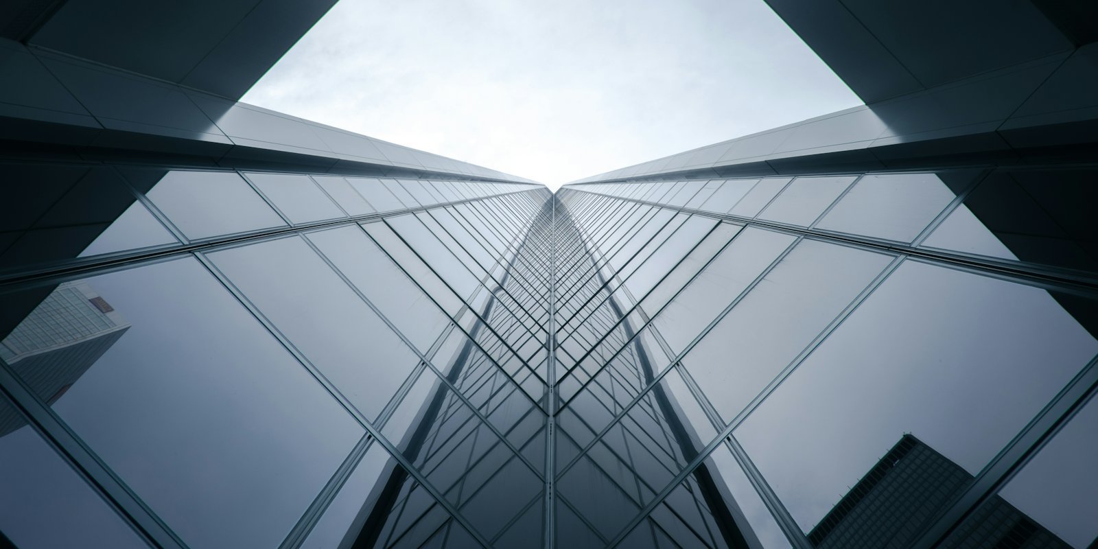 A glass office tower seen from directly below, converging to a point.
