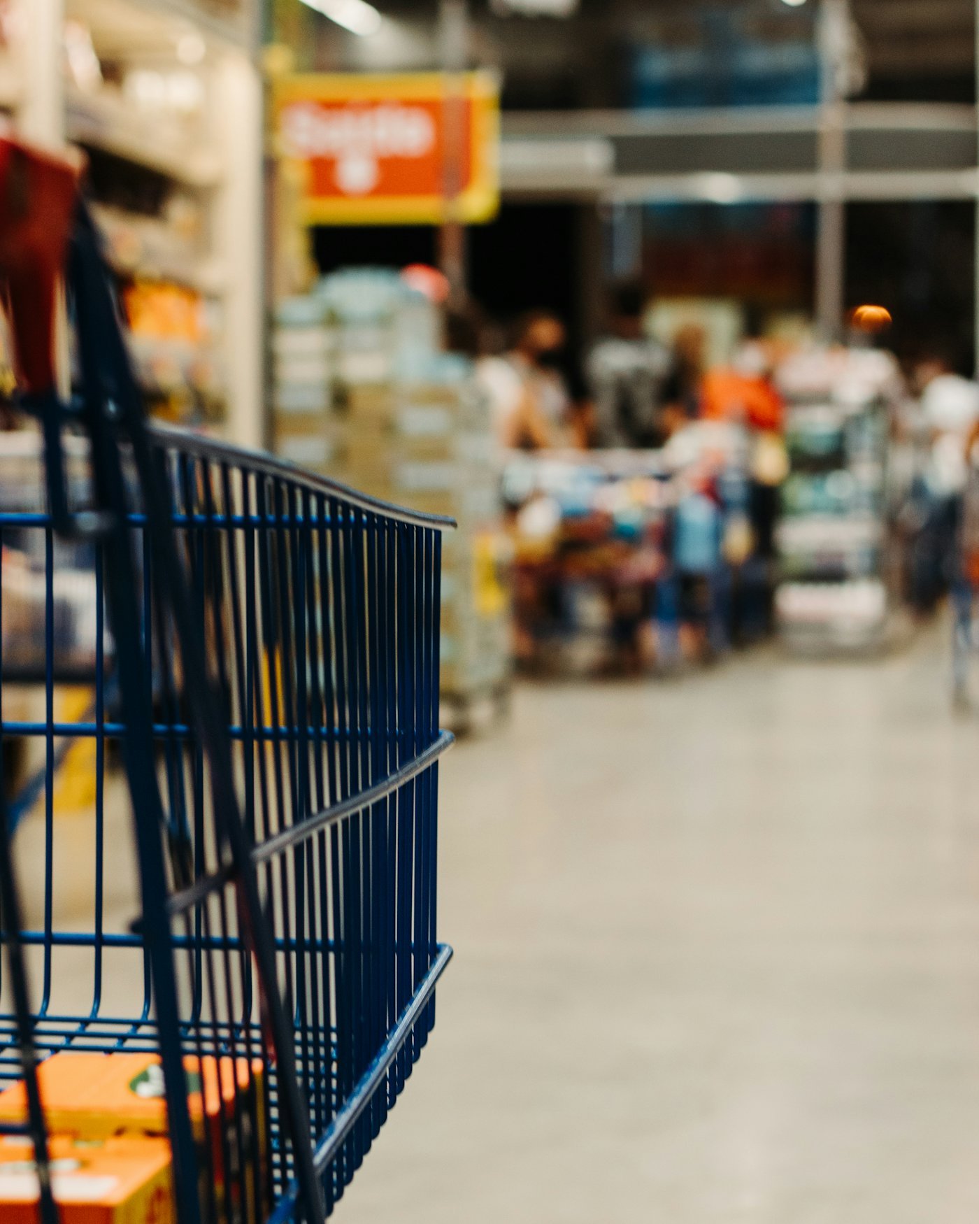 An empty shopping cart in a supermarket aisle.