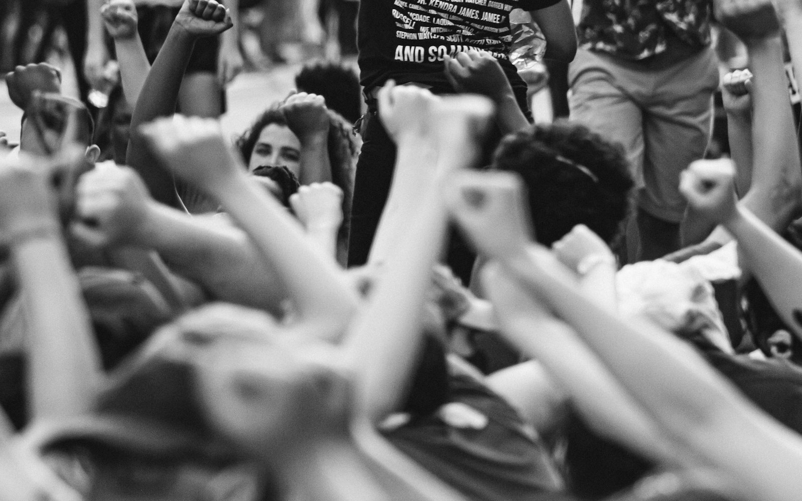 A crowd of raised fists, photographed in black and white.