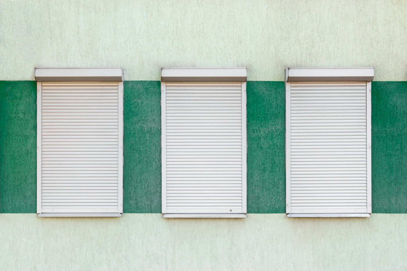 A row of closed metal roller shutters on shopfronts.