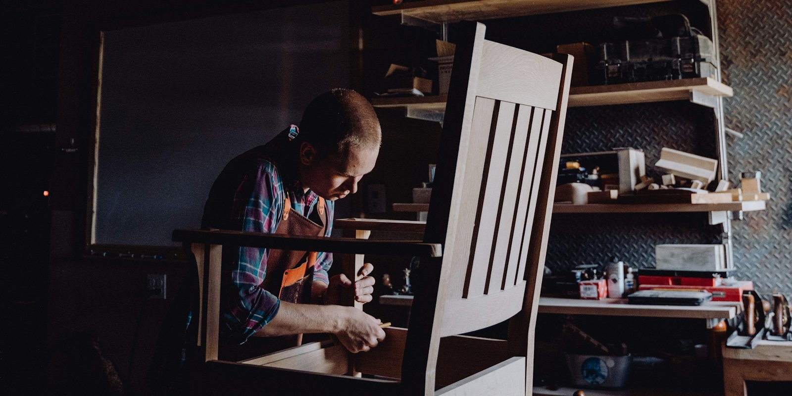 A maker in a workshop assembling a wooden chair by hand.
